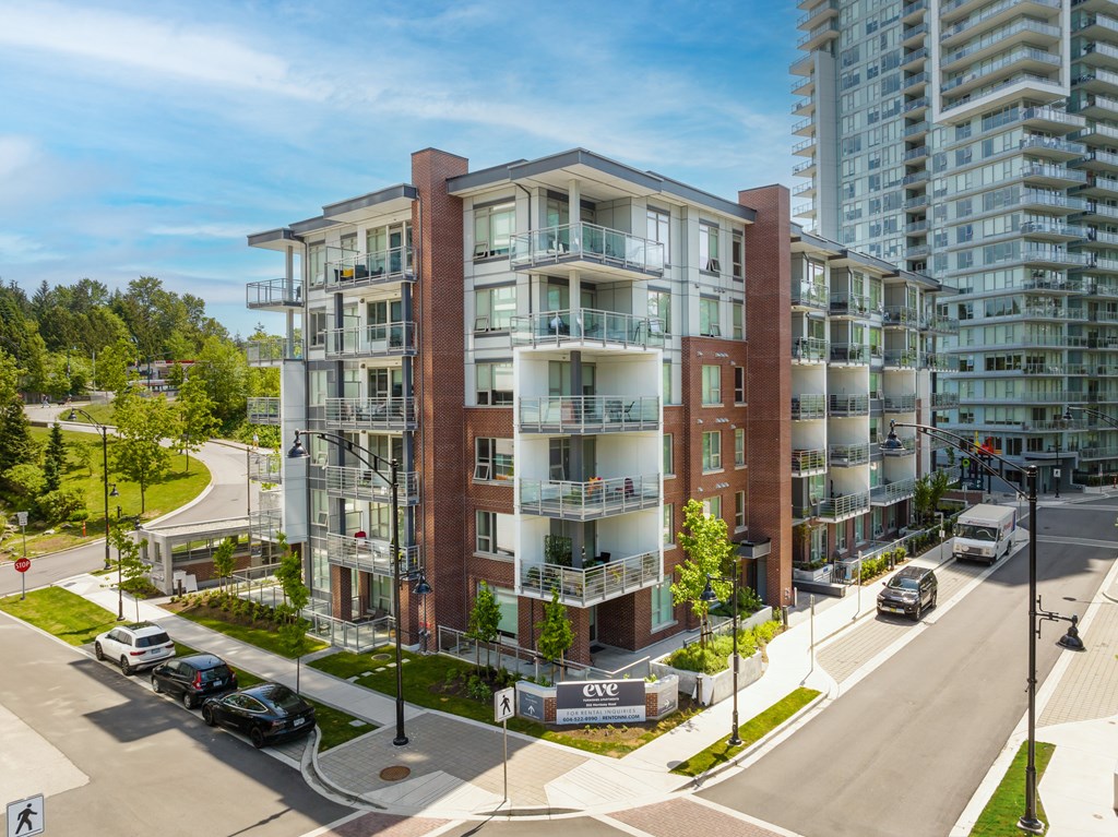 A modern apartment building with a parking lot in front.