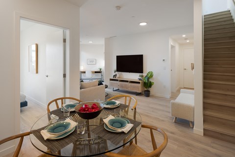A modern dining room with a glass table set for four.