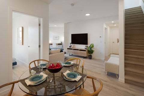 A modern dining room with a glass table set for four.