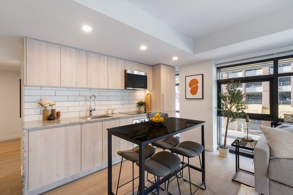 A modern kitchen with a black table and chairs.