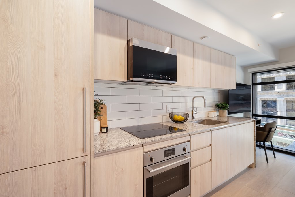 A modern kitchen with wooden cabinets and a black microwave above the stove.
