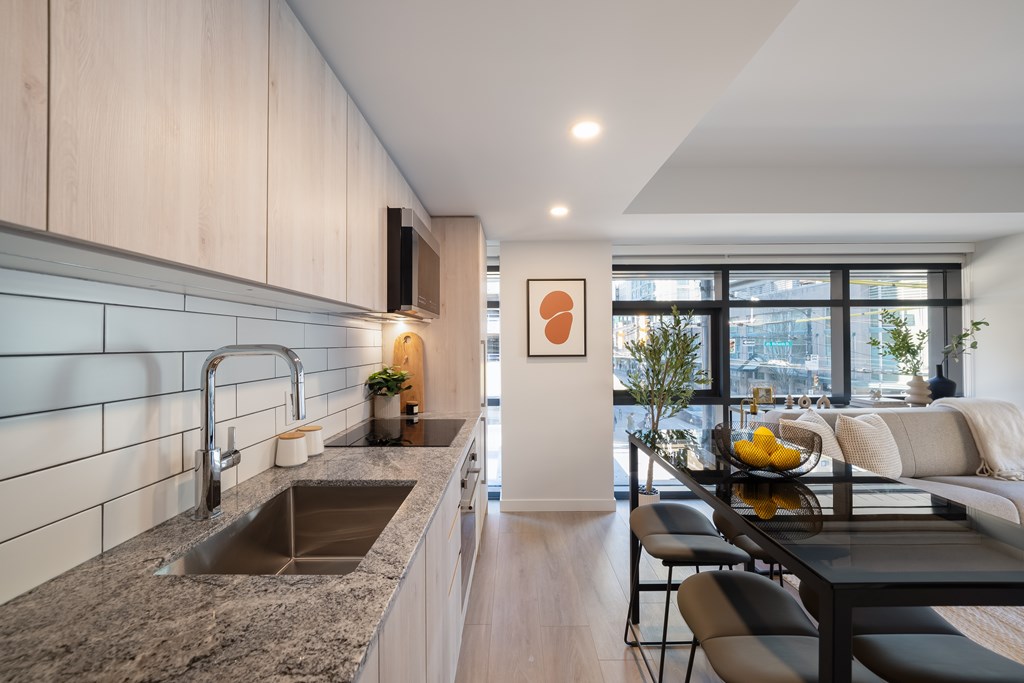 A modern kitchen with a granite countertop and a dining table set for two.