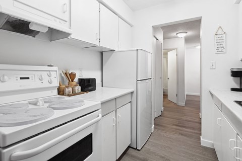 A white kitchen with a stove, oven, and refrigerator.