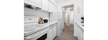 A white kitchen with a stove, oven, and refrigerator.