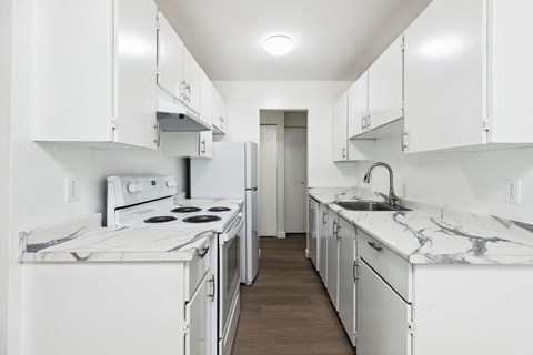A white kitchen with a marble counter top.
