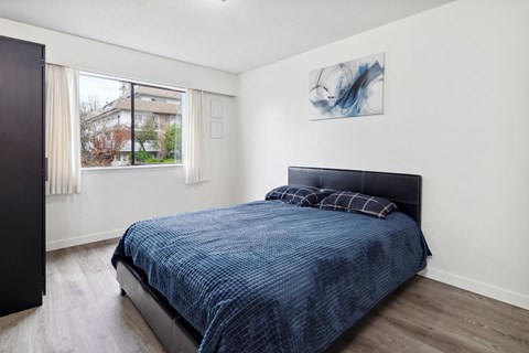 A bedroom with a blue bedspread and a black headboard.