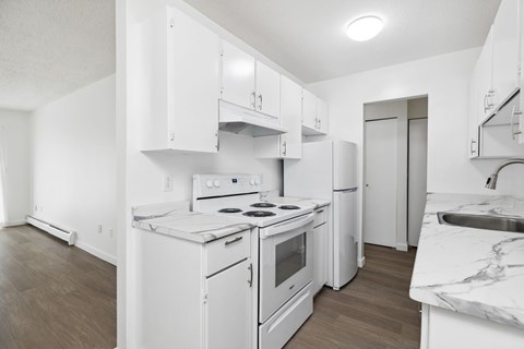 A white kitchen with a stove, oven, and refrigerator.
