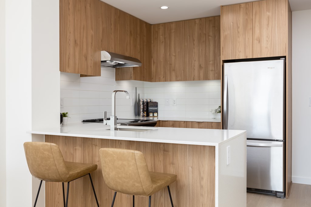 A modern kitchen with wooden cabinets and a white countertop.