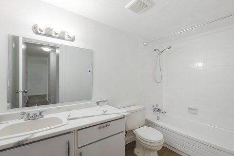 A white bathroom with a toilet, sink, and bathtub.