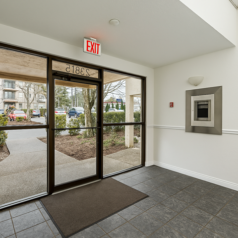 A white wall with a red exit sign above a door.