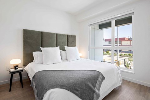 A bedroom with a large bed and a window overlooking a balcony.