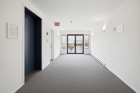 A hallway with a red exit sign above the door.