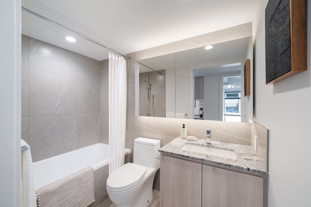 A modern bathroom with a white toilet, sink, and bathtub.