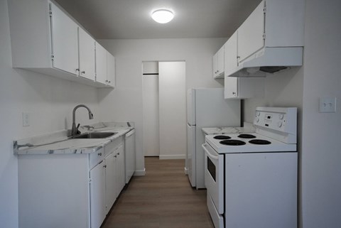 A kitchen with white appliances and cabinets.