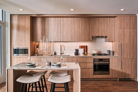 A modern kitchen with wooden cabinets and a marble island.