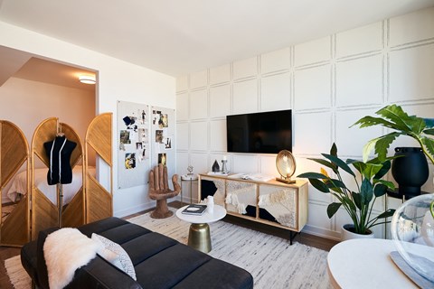 A modern living room with a black couch and a white wall.