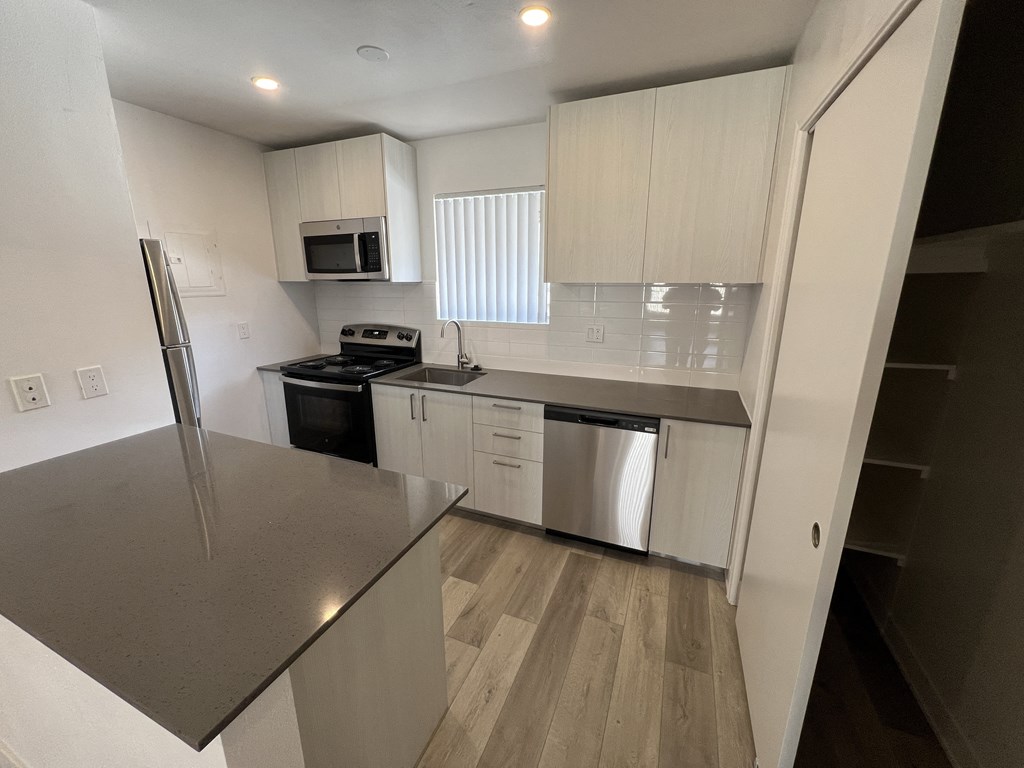 an empty kitchen with stainless steel appliances and white cabinets