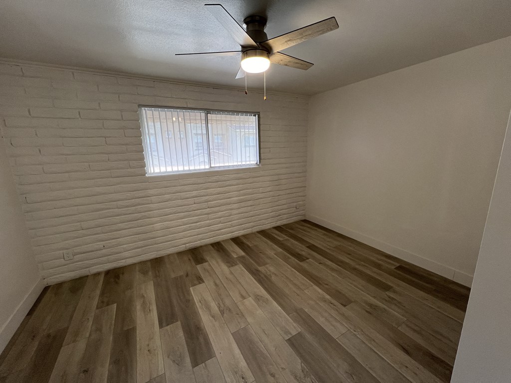 an empty living room with wood flooring and a ceiling fan