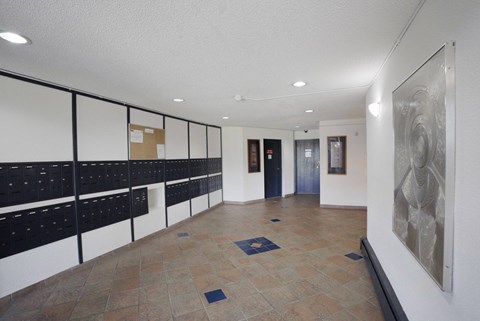 A hallway with a row of mailboxes on the left and a painting on the right.