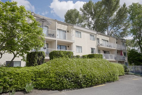 Apartment building with green bushes in front.