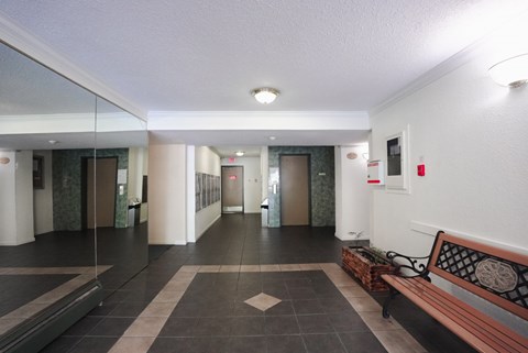 A hallway with a bench and a fire extinguisher on the wall.