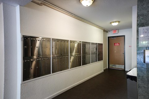 A long hallway with a door at the end and a red exit sign above it.