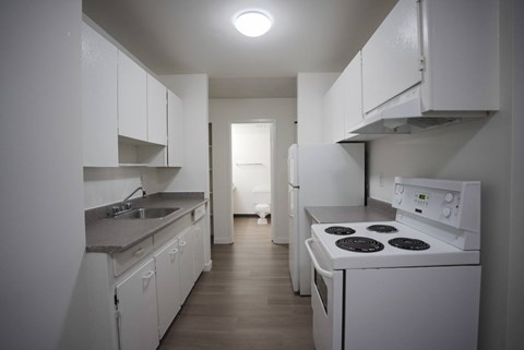 A white kitchen with a stove and sink.