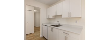 A kitchen with white cabinets and a white sink.