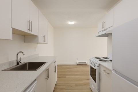 A kitchen with white cabinets and a stove top oven.
