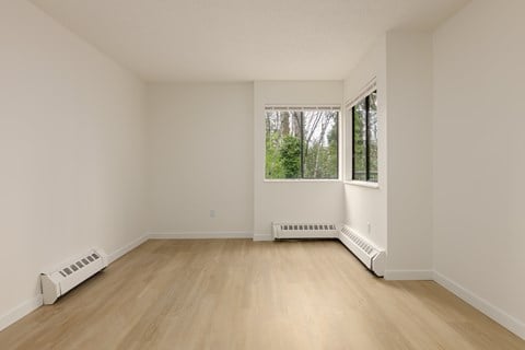 A room with a window and a white wall.