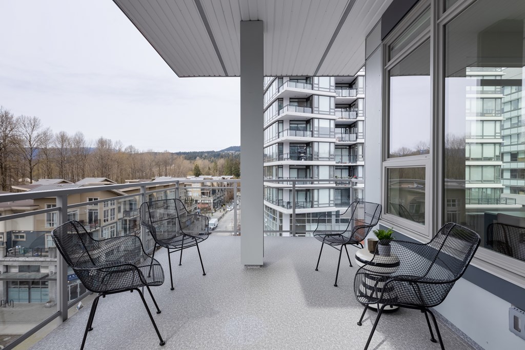 A balcony with chairs and a table with a plant on it.