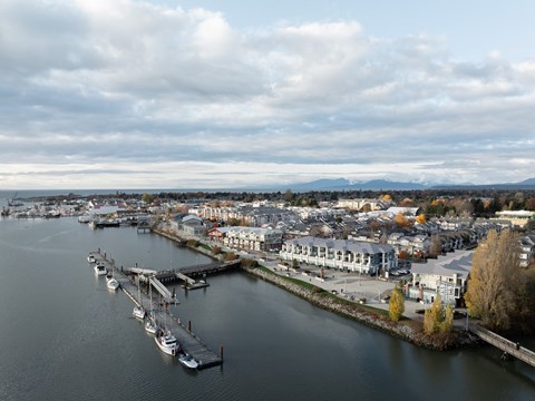 A marina with boats docked and buildings in the background.