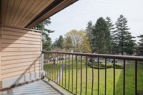 A balcony with a metal railing overlooking a grassy area.