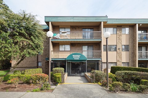 The image shows a multi-story apartment building with a green awning and a black gate.