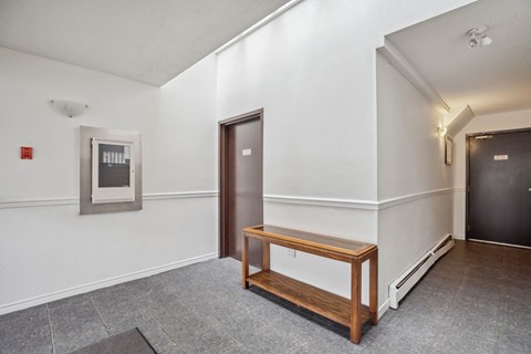 A hallway with a bench and a door.