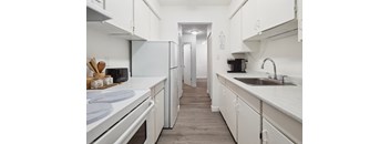 A kitchen with white appliances and cabinets.