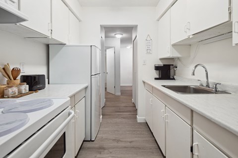 A kitchen with white appliances and cabinets.