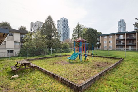 A playground with a green slide and a red and blue swing set.