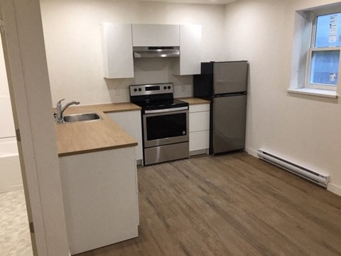 A kitchen with a stove top oven, refrigerator, and sink.