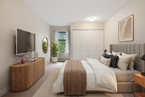 A bedroom with a large bed and a flat screen TV on a wooden cabinet.
