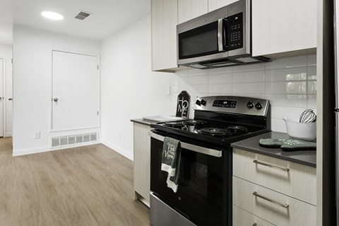 A modern kitchen with a black stove top oven and white cabinets.