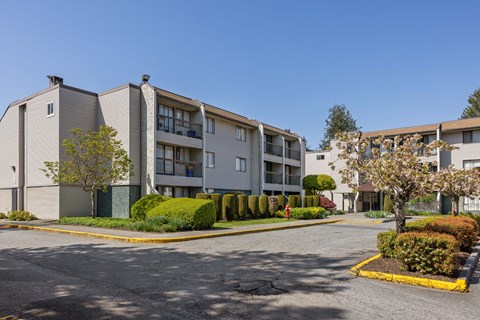 Apartment complex with a parking lot in front.