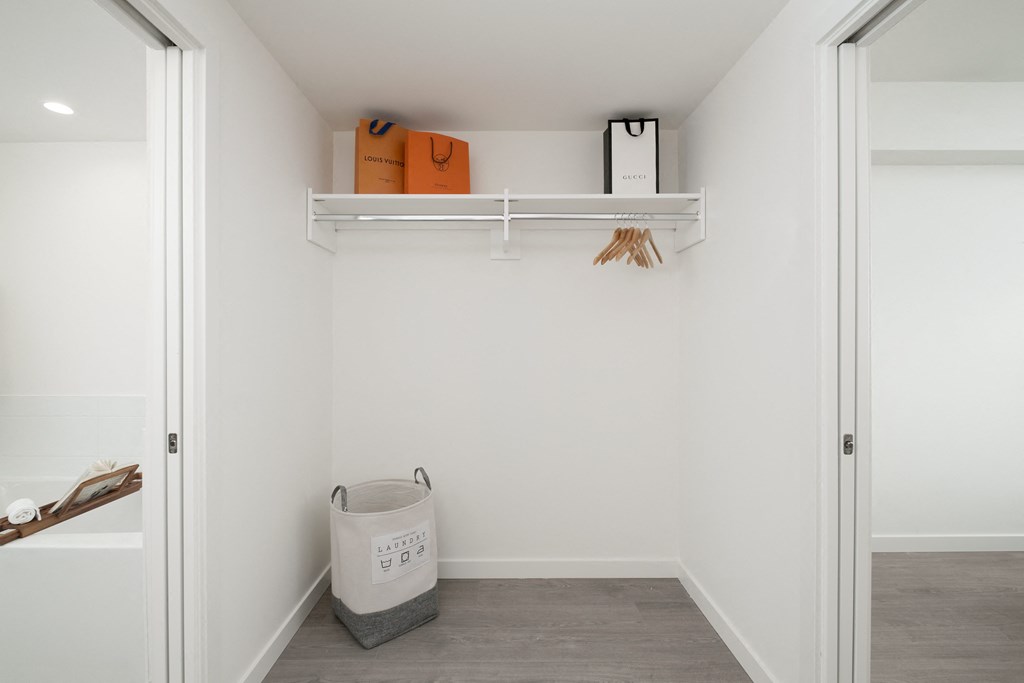 a small laundry room with a basket and shelves on the wall