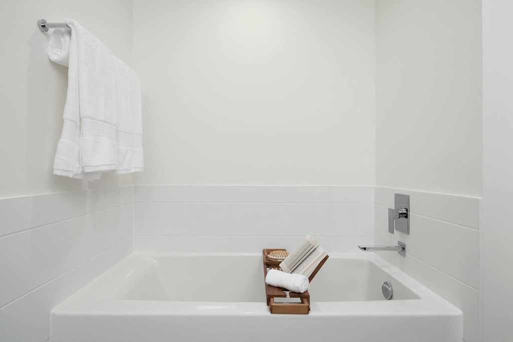 a white bathroom with a bath tub and a towel
