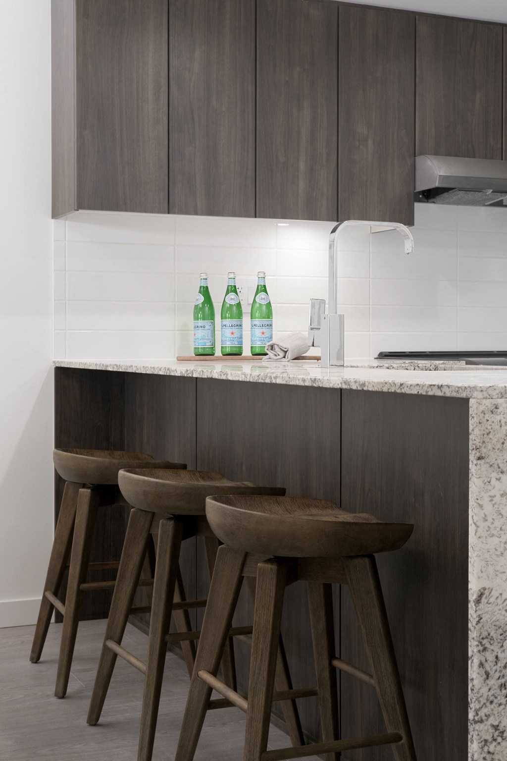 a kitchen with three wooden stools in front of a counter top