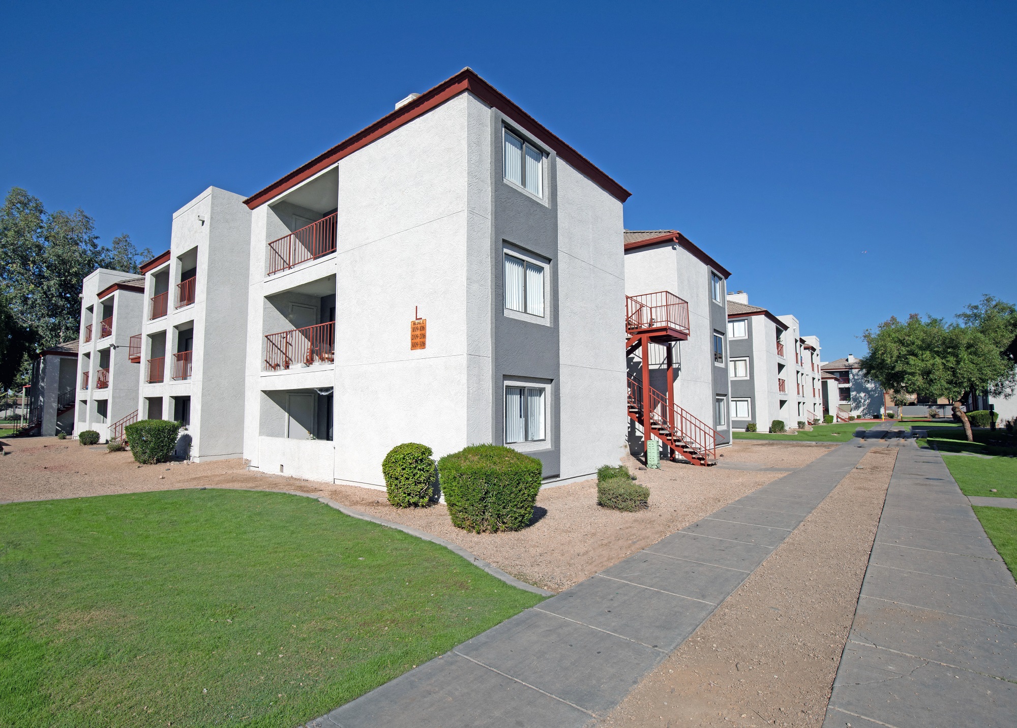 an exterior view of an apartment building with a sidewalk and green grass