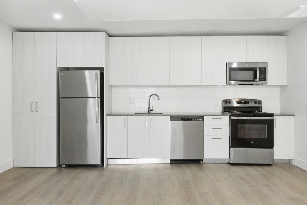a white kitchen with stainless steel appliances and white cabinets