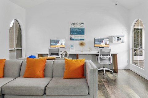 A living room with a grey couch and orange pillows.