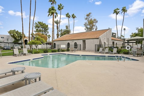 A pool surrounded by palm trees and a building. at Central on Broadway Apartments, Mesa, 85202