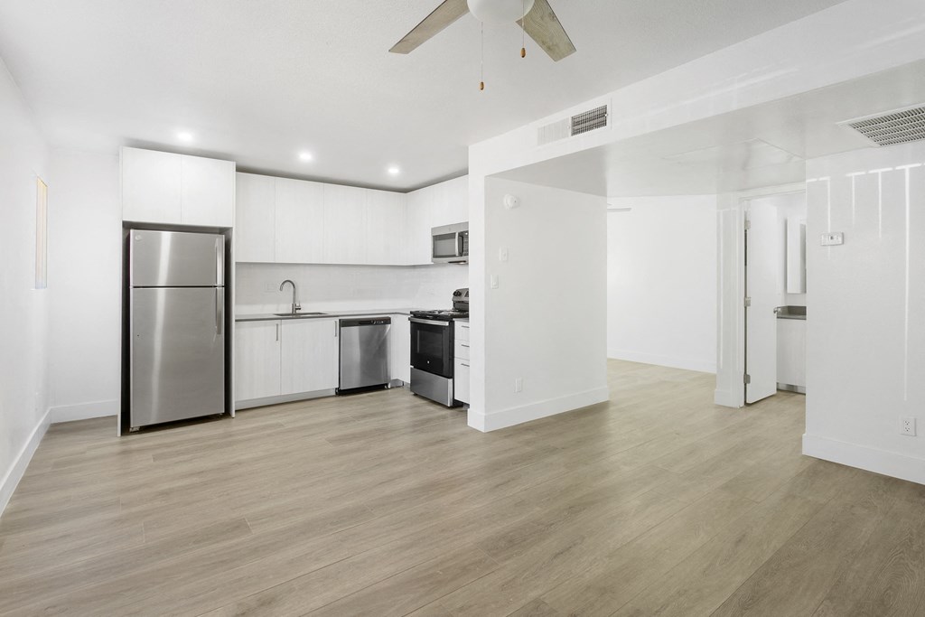 a renovated living room and kitchen with white walls and wood floors